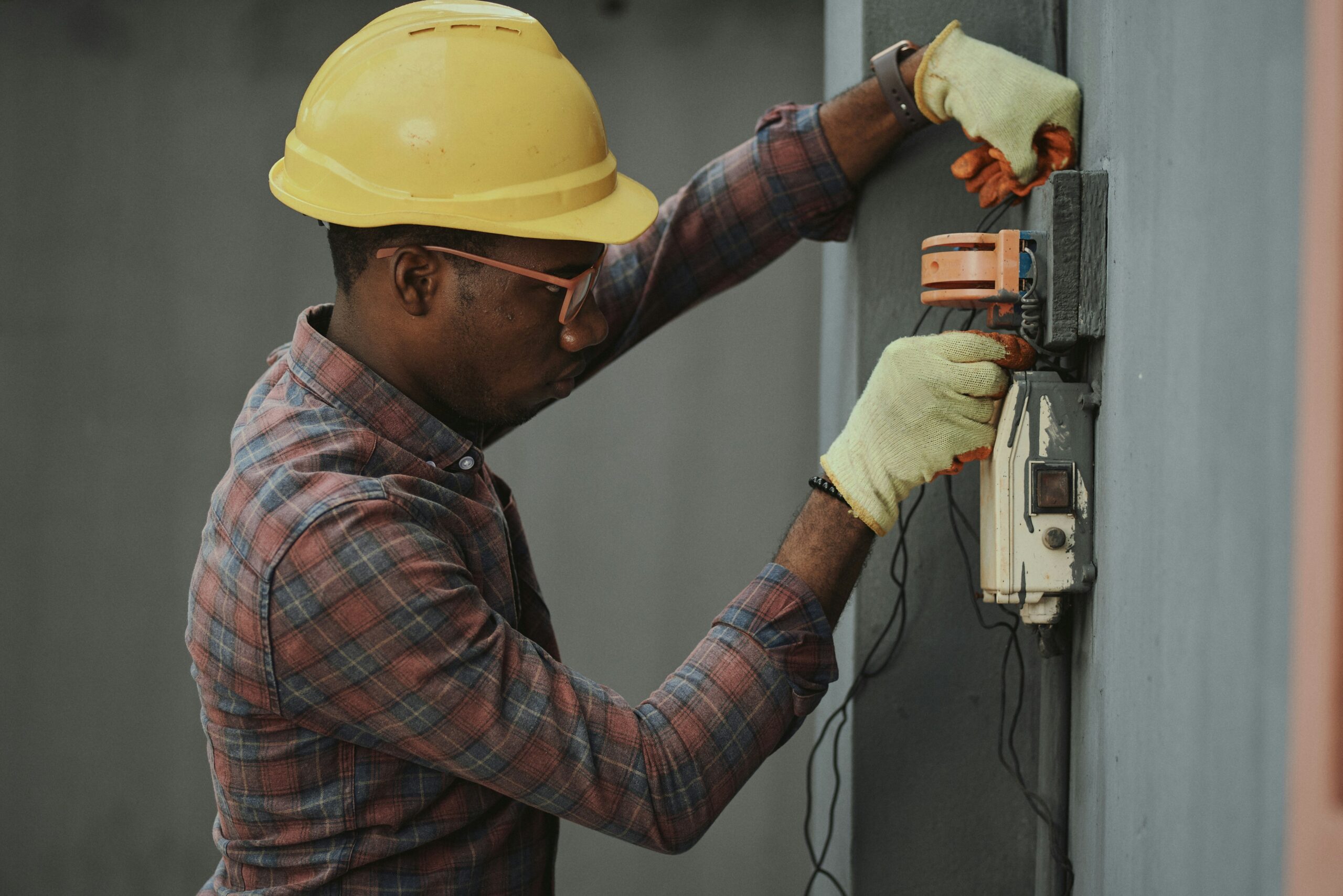 Electrician wearing PPE while working on an industrial electrical panel